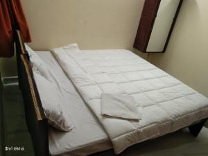a bed with white sheets on it in a room at Babu Naidu Residency in Vellore