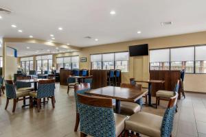 a dining room with tables and chairs and windows at Comfort Suites in Macon