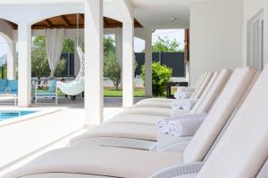 a row of white lounge chairs next to a pool at Luxurious private family resort with mountain view in Šestanovac