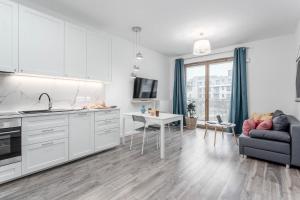 eine Küche und ein Wohnzimmer mit einem Sofa und einem Tisch in der Unterkunft Chill Apartments Wilanów in Warschau
