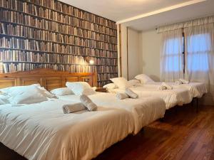 três camas num quarto com uma grande parede de livros em Hotel Eriste em Eriste