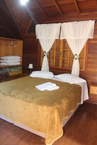 a bedroom with a bed with two towels on it at Pousada Floresta Negra in Canela