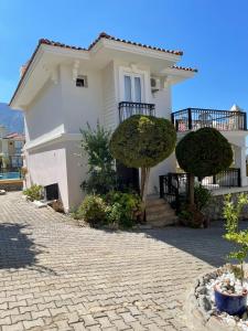 una casa blanca con dos árboles delante de ella en Wonderful Villa In Oludeniz 2, en Kayakoy