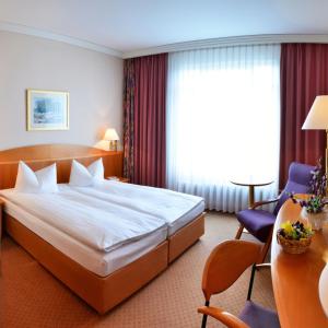 ein Hotelzimmer mit einem großen Bett und einem Stuhl in der Unterkunft Hotel Meerane in Meerane