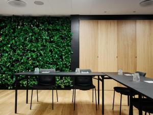 a meeting room with two tables and a green wall at Hotel Oasia Aarhus City in Aarhus