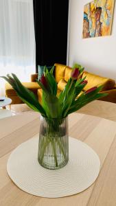 a vase with flowers in it sitting on a table at Przystań Letników by MYPART in your apartment in Gdańsk