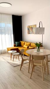ein Wohnzimmer mit einem gelben Sofa und Tischen in der Unterkunft Przystań Letników by MYPART in your apartment in Danzig