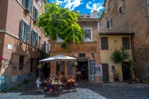 un grupo de personas sentadas en mesas bajo un paraguas en un callejón en Navona Open Space Apartments, en Roma