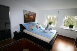 a bedroom with a bed with blue sheets and two windows at Ferienwohnungen Wyk/Föhr in Wyk auf Föhr