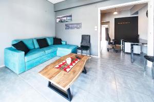 ein Wohnzimmer mit einem blauen Sofa und einem Tisch in der Unterkunft Topfloor central apt with urban views,3' to metro in Athen