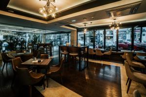 um restaurante com mesas, cadeiras e janelas em MARK Hotel em Belgrado