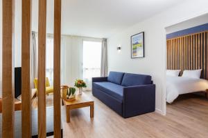 a hotel room with a blue couch and a bed at Résidence Coeur Comédie in Montpellier