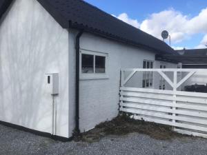 une maison blanche avec une clôture et un portail blanc dans l'établissement Feriehus - Marielyst centrum, à Bøtø By