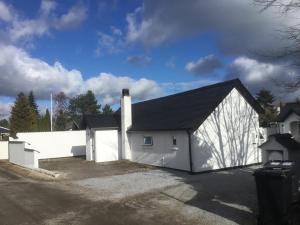 a white building with a black roof at Feriehus - Marielyst centrum in Marielyst