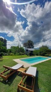 a pool with two chairs and a table next to it at Entre Las Sierras Tiny House Solo Adultos in Villa Giardino