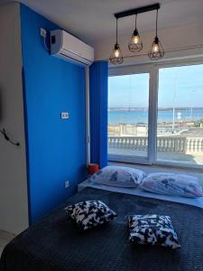 a blue bedroom with a bed with a large window at Apartman Pandula in Tkon