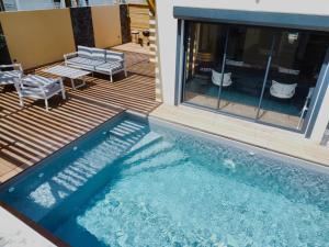 a swimming pool with two chairs and a table at Villa Jasmin Standing Piscine Chauffee 4 Ch 9 Pers in Baie-Mahault
