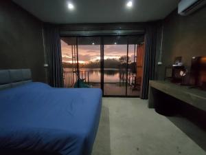 a bedroom with a bed and a view of a lake at Kram Farmstay in Nakhon Pathom