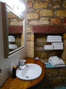 baño con lavabo y pared de piedra en La Tinaia, en Bosa Marina
