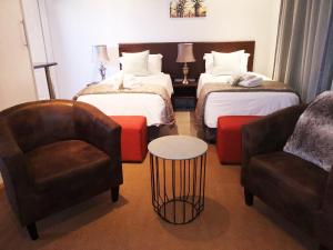 una camera d'albergo con due letti e una sedia di Lesolo Lodge a Burgersfort