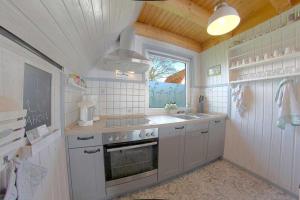 a kitchen with a stove and a sink and a window at SR VS1 Haus Ellie in Dorum-Neufeld