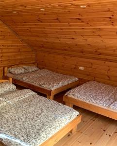 three beds in a room with wooden walls at Gerovės sodybėlė in Garliava