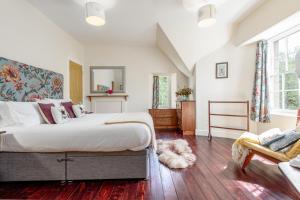 a bedroom with a large bed and a chair at Gardener's Cottage in Crieff