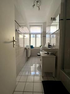 a white bathroom with a sink and a mirror at R&L Apartment Karl-Heine-Strasse OG in Leipzig