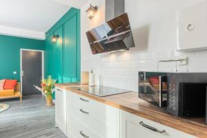 a kitchen with white cabinets and a black microwave at Le Selah in Tourcoing