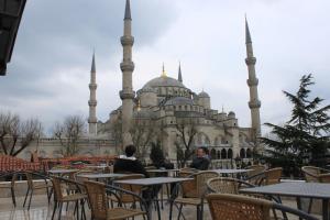 two people sitting at tables in front of a mosque at Hotel SultanHill in Istanbul