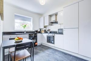 a kitchen with white cabinets and a table with a bowl of fruit at Stylish Two Bedroom Apartment With Free Parking! in Romford