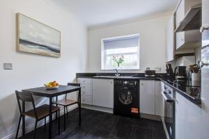 a kitchen with a washing machine and a table at Stylish Two Bedroom Apartment With Free Parking! in Romford