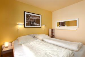 Un dormitorio con una cama blanca con una foto en la pared en Strandhotel 14, en Laboe