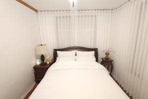 łóżko z białą pościelą i poduszkami w sypialni w obiekcie Stay Hwangchon w mieście Gyeongju