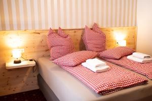 una cama con sábanas y almohadas rojas y blancas a cuadros. en Rösslgut Bed & Breakfast, en Zederhaus