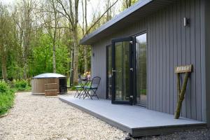 ein Haus mit einer Veranda mit einem Tisch und einer Bank in der Unterkunft Lakeside Eco Lodge- 'Heron' in Bishampton + 10 Fotos