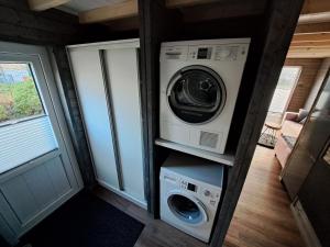 Tiny House Flensburg Lee في هاندي فيت: غسالة ومجفف في منزل صغير