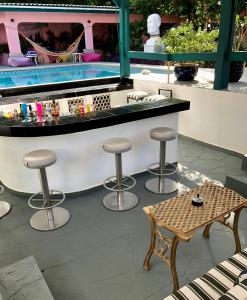 un bar con taburetes junto a una piscina en Mini boutique resort exclusively for your family or friends en Willemstad