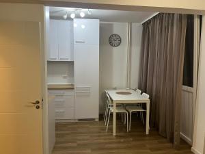 una pequeña cocina blanca con mesa y sillas en Apartman 9, en Voždivac