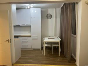 una pequeña cocina blanca con mesa y reloj en Apartman 9, en Voždivac