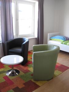 Zimmer mit 2 Stühlen, einem Tisch und einem Bett in der Unterkunft Bahnhofstr Apartment in Castrop-Rauxel