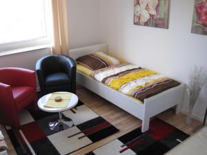 ein kleines Schlafzimmer mit einem Bett und einem Stuhl in der Unterkunft Bahnhofstr Apartment in Castrop-Rauxel