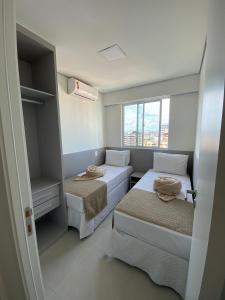 Cette petite chambre comprend 2 lits et une fenêtre. dans l'établissement Edifício Promenade II Apt 1108 -Mandi Hospitalidade, à Maceió