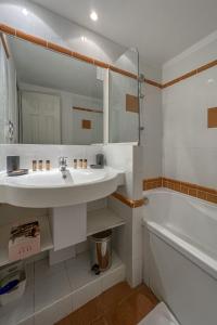 een badkamer met een wastafel, een bad en een spiegel bij Appartement Pheonix YourHostHelper in Gujan-Mestras