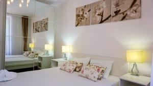 een slaapkamer met een wit bed met kussens en een spiegel bij Byala Cliff Sea View Penthouse in Byala