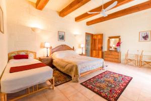 a bedroom with two beds and a ceiling fan at Stunning 3 bedroom Farmhouse with pool in Xagħra