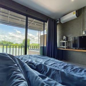 a bedroom with a blue bed with a large window at Kram Farmstay in Nakhon Pathom