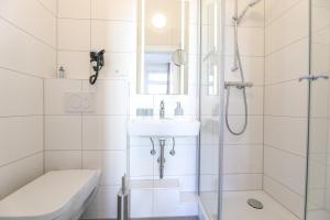 een witte badkamer met een wastafel en een douche bij Haus Inselanker Kajüte 05 in Norderney