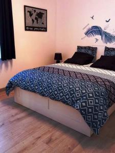 a bedroom with a bed with a blue and white comforter at Le Watt'else in Watten