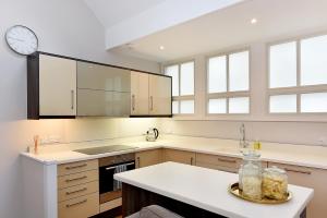 a kitchen with white counters and a clock on the wall at London Choice Apartments - South Kensington - Mews House II in London